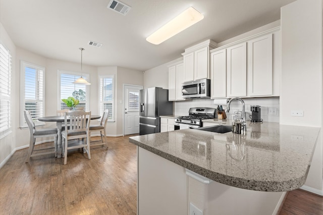 kitchen featuring kitchen peninsula, white cabinetry, hardwood / wood-style flooring, sink, and stainless steel appliances