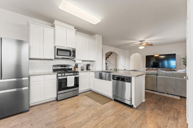 kitchen with kitchen peninsula, white cabinets, stainless steel appliances, and sink