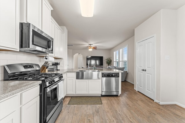 kitchen featuring white cabinetry, kitchen peninsula, appliances with stainless steel finishes, and light wood-type flooring