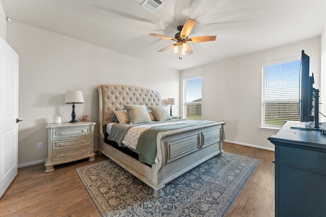 bedroom featuring ceiling fan, multiple windows, and dark hardwood / wood-style flooring