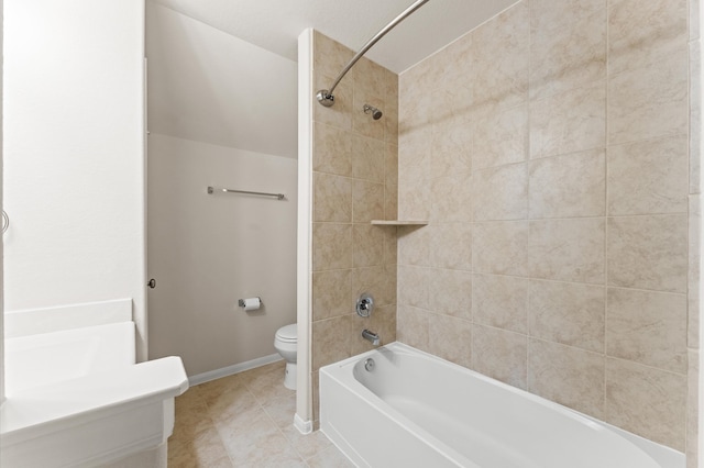 bathroom featuring toilet, tiled shower / bath, and tile patterned flooring