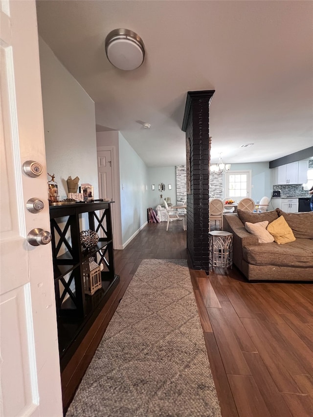 hallway featuring dark wood-type flooring and a chandelier