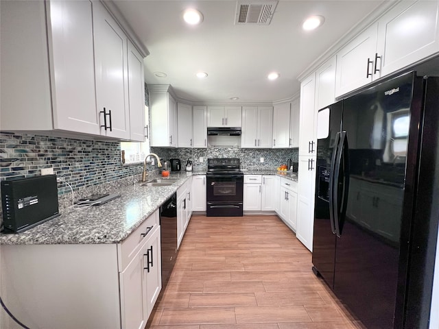 kitchen featuring sink, black appliances, white cabinets, and light hardwood / wood-style flooring