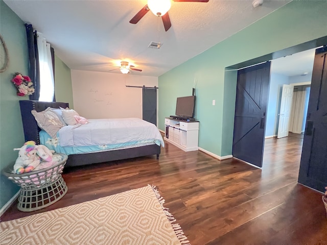 bedroom with dark wood-type flooring, a barn door, a textured ceiling, and ceiling fan