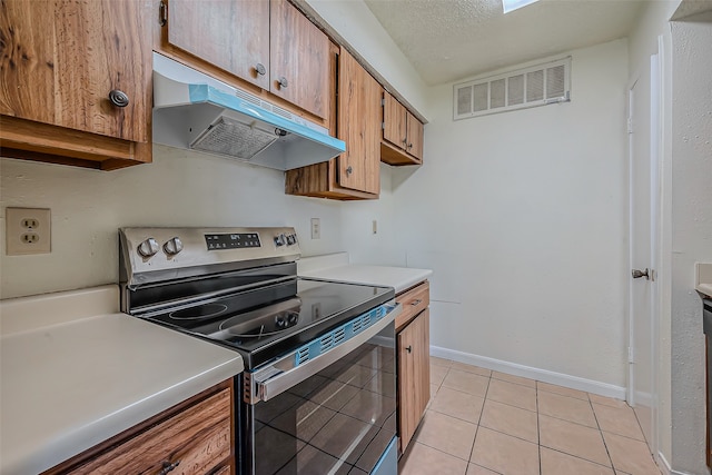 kitchen featuring stainless steel electric range, a textured ceiling, and light tile patterned floors