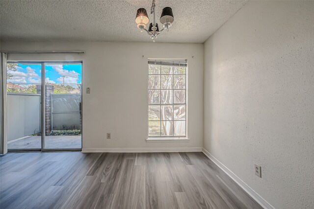 spare room featuring a chandelier, hardwood / wood-style flooring, and a textured ceiling