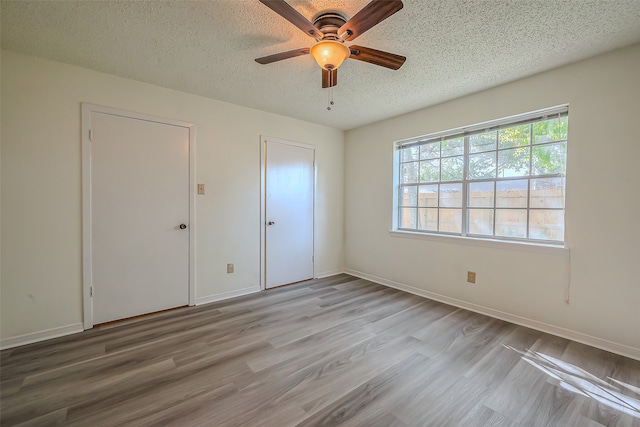 unfurnished bedroom with light hardwood / wood-style flooring, a textured ceiling, and ceiling fan