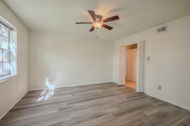 spare room with a textured ceiling, light wood-type flooring, and ceiling fan