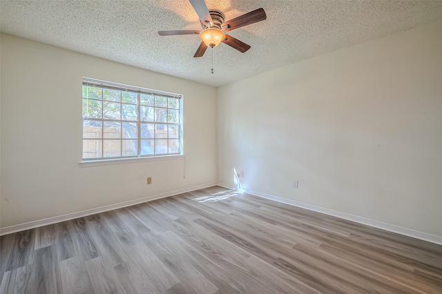 unfurnished room with a textured ceiling, light wood-type flooring, and ceiling fan