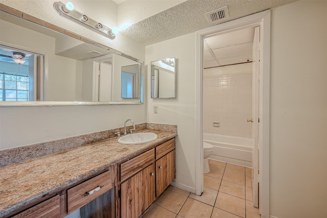 full bathroom featuring toilet, tile patterned flooring, tiled shower / bath combo, vanity, and a textured ceiling