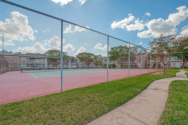 view of tennis court featuring a lawn