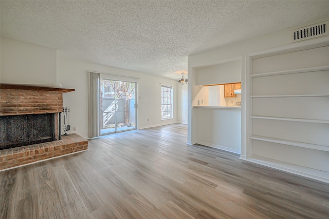 unfurnished living room featuring a fireplace, a textured ceiling, and light wood-type flooring