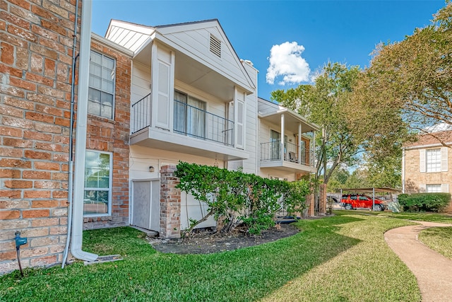 exterior space with a yard, a carport, and a balcony