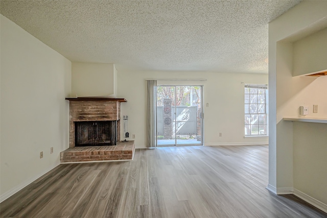 unfurnished living room with a textured ceiling, wood-type flooring, and a brick fireplace