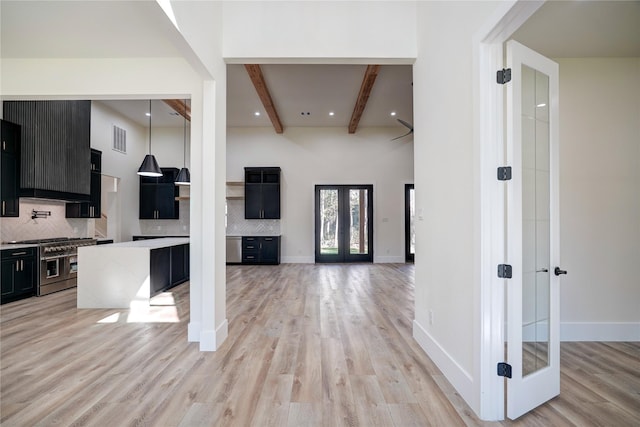 interior space featuring decorative backsplash, french doors, beamed ceiling, and range with two ovens