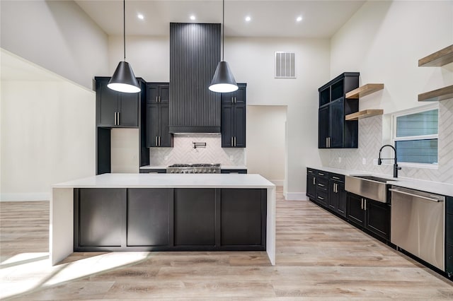 kitchen with pendant lighting, sink, stainless steel dishwasher, light hardwood / wood-style floors, and a kitchen island