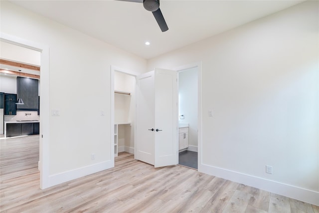 unfurnished bedroom featuring a walk in closet, ceiling fan, a closet, and light hardwood / wood-style floors