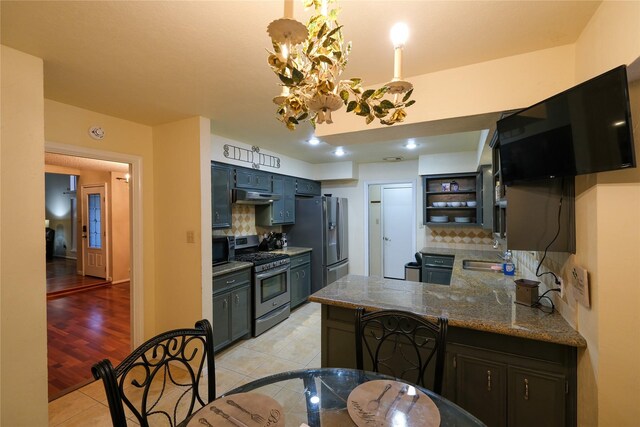 kitchen featuring sink, tasteful backsplash, kitchen peninsula, light tile patterned floors, and appliances with stainless steel finishes