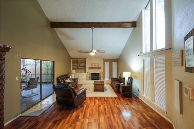 living room with hardwood / wood-style flooring, ceiling fan, beam ceiling, and a fireplace