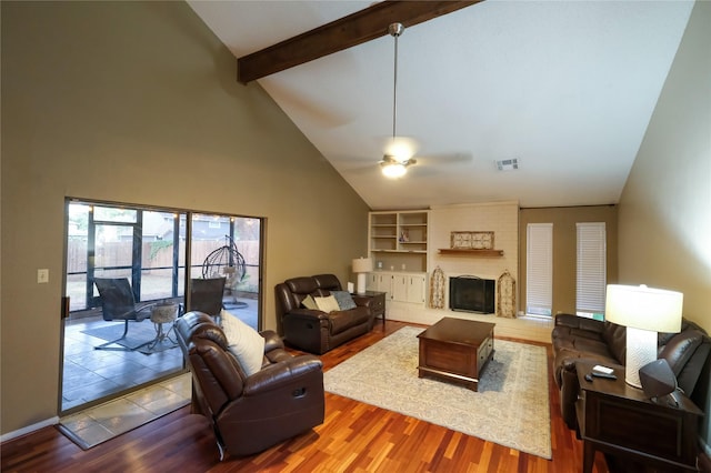 living room featuring ceiling fan, built in features, beamed ceiling, high vaulted ceiling, and a fireplace