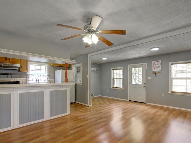 kitchen featuring white fridge, ceiling fan, a textured ceiling, and light wood-type flooring