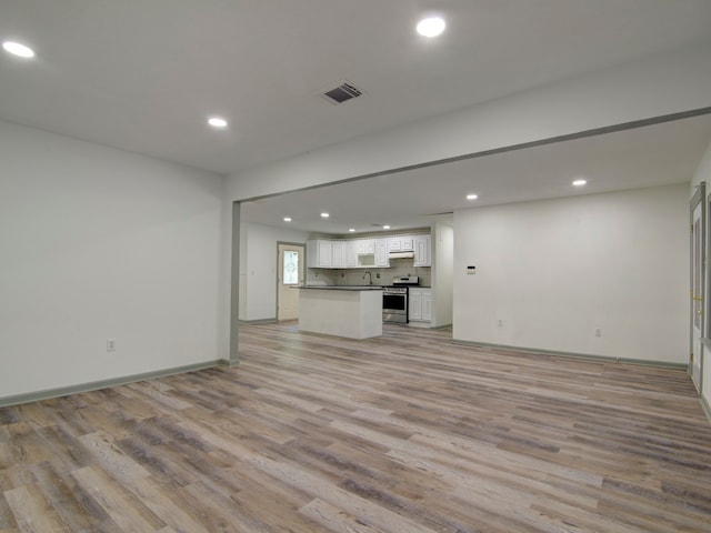 unfurnished living room featuring sink and light hardwood / wood-style floors