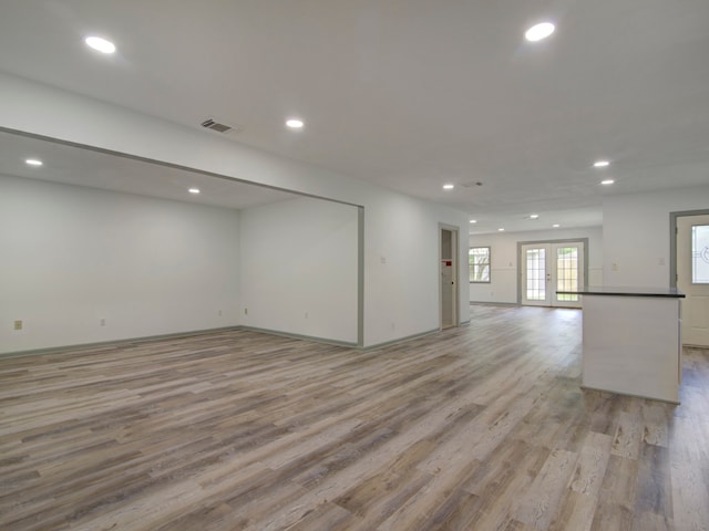 unfurnished living room with french doors and light hardwood / wood-style flooring