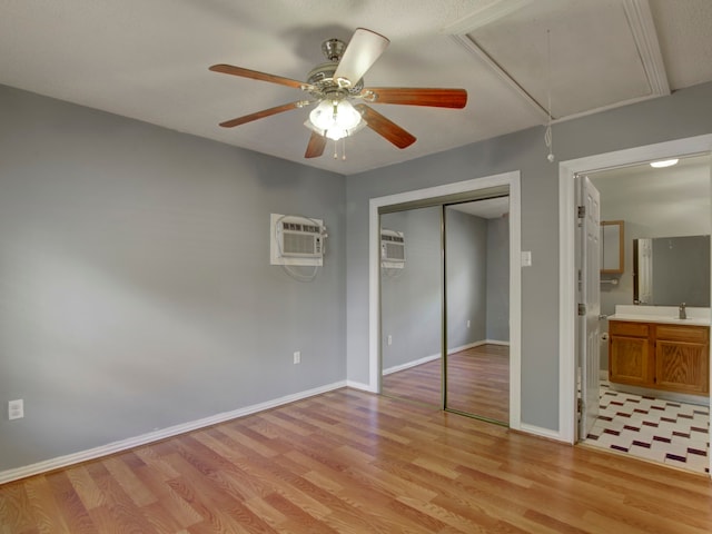 unfurnished bedroom featuring light hardwood / wood-style flooring, a closet, a wall mounted AC, and ceiling fan