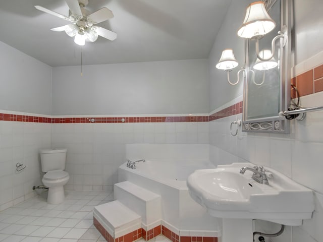 bathroom with a bath, toilet, tile patterned floors, and tile walls