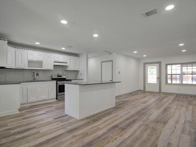 kitchen featuring light hardwood / wood-style floors, white cabinetry, stainless steel range oven, and tasteful backsplash