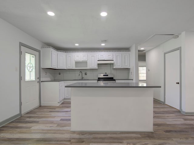 kitchen featuring white cabinets, stove, light wood-type flooring, and a kitchen island