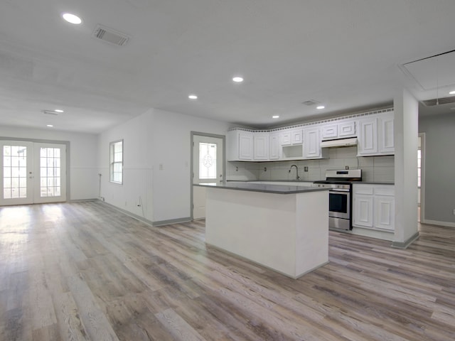 kitchen featuring light hardwood / wood-style floors, white cabinetry, stainless steel stove, and backsplash