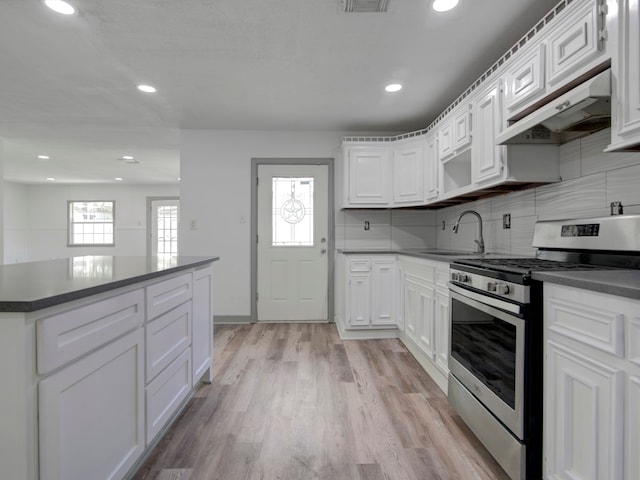 kitchen with custom exhaust hood, white cabinets, stainless steel range oven, and a wealth of natural light