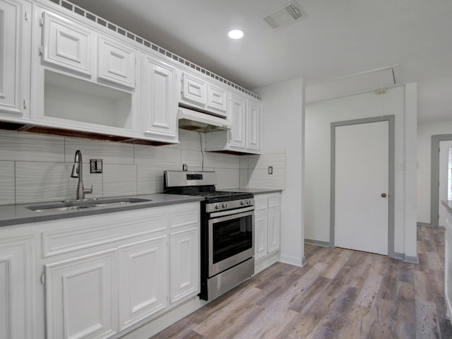 kitchen with extractor fan, white cabinetry, stainless steel stove, light hardwood / wood-style floors, and sink