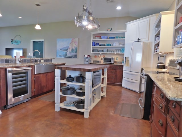 kitchen with butcher block counters, white refrigerator with ice dispenser, hanging light fixtures, stainless steel stove, and beverage cooler