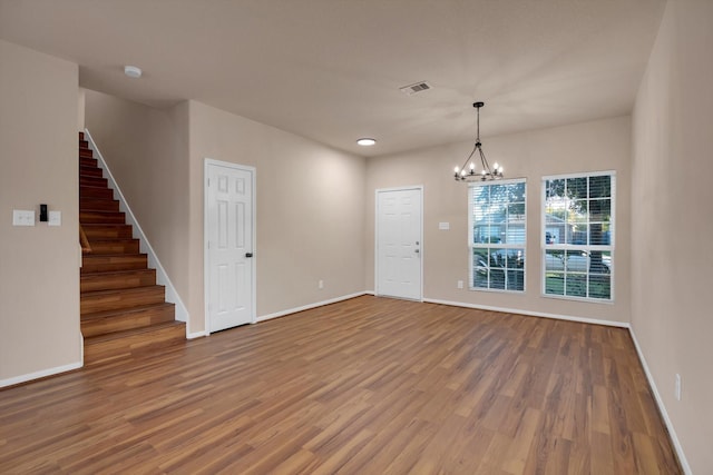 spare room with wood-type flooring and a notable chandelier