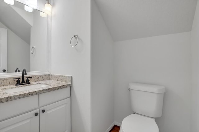 bathroom featuring vanity, toilet, and vaulted ceiling