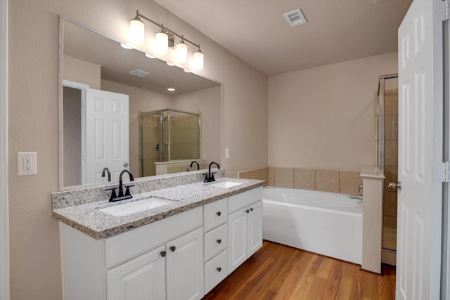 bathroom featuring hardwood / wood-style floors, vanity, and plus walk in shower