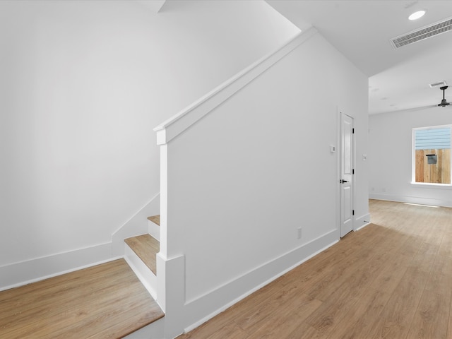 stairs featuring wood-type flooring and ceiling fan