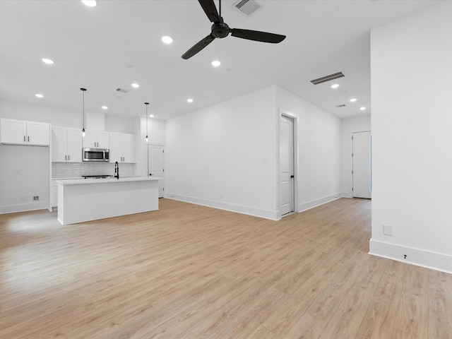 unfurnished living room with light hardwood / wood-style flooring, sink, and ceiling fan