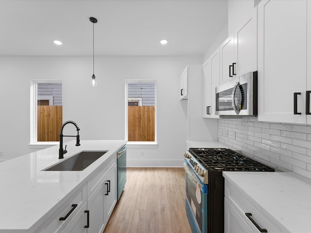 kitchen featuring sink, appliances with stainless steel finishes, decorative light fixtures, and white cabinetry