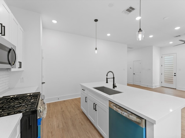 kitchen featuring sink, an island with sink, hanging light fixtures, stainless steel appliances, and white cabinets