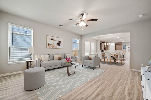 living room with light hardwood / wood-style floors and ceiling fan with notable chandelier