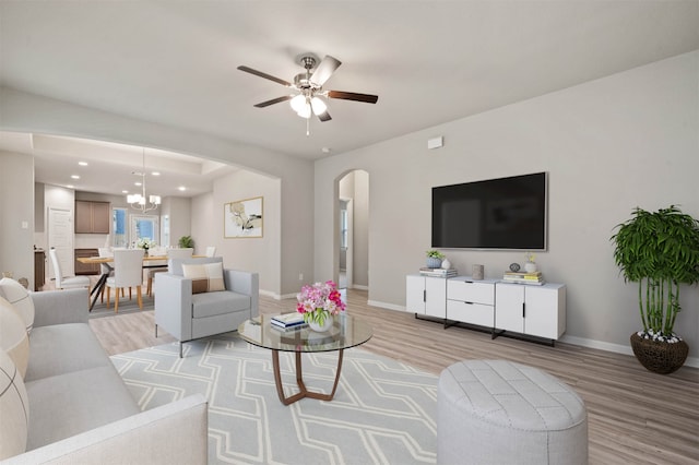 living room featuring light hardwood / wood-style flooring and ceiling fan with notable chandelier