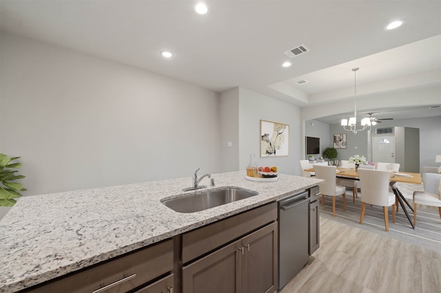 kitchen featuring dishwasher, sink, pendant lighting, light stone counters, and light hardwood / wood-style floors