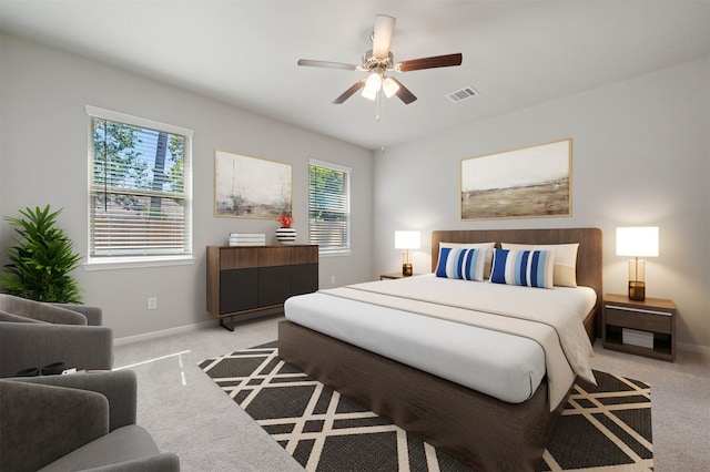 bedroom with multiple windows, light colored carpet, and ceiling fan