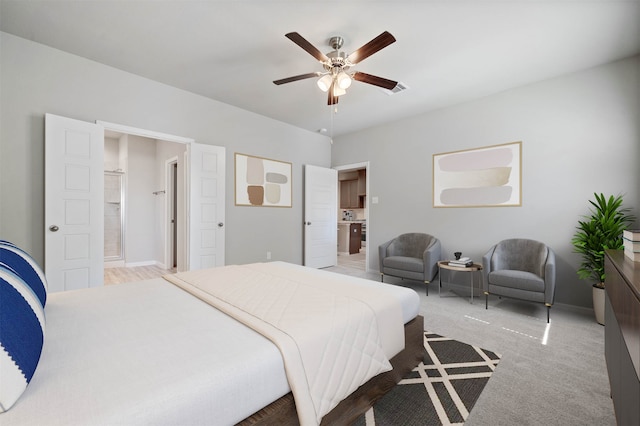 carpeted bedroom with ensuite bathroom and ceiling fan