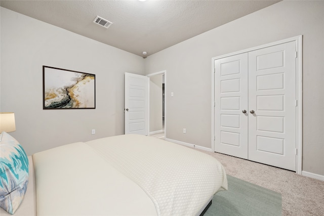 carpeted bedroom featuring a closet and a textured ceiling