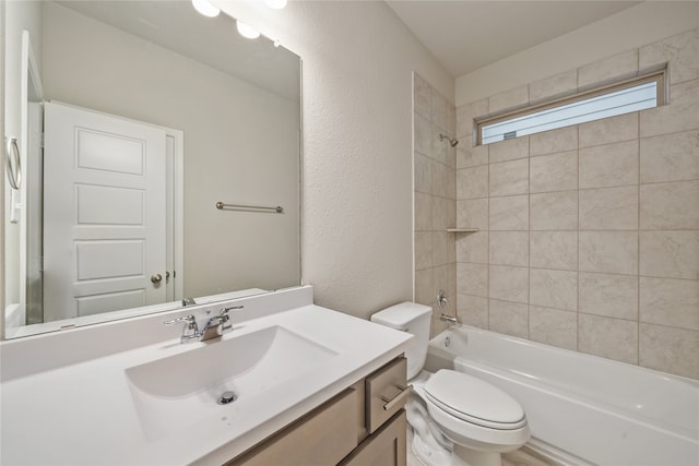 full bathroom with toilet, tiled shower / bath, and vanity