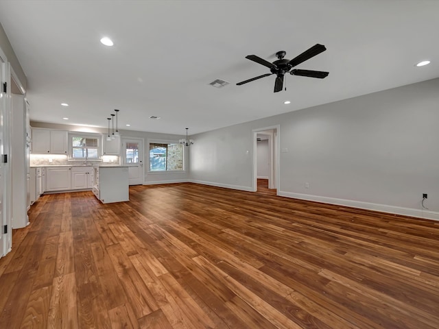 unfurnished living room with sink, wood-type flooring, and ceiling fan with notable chandelier